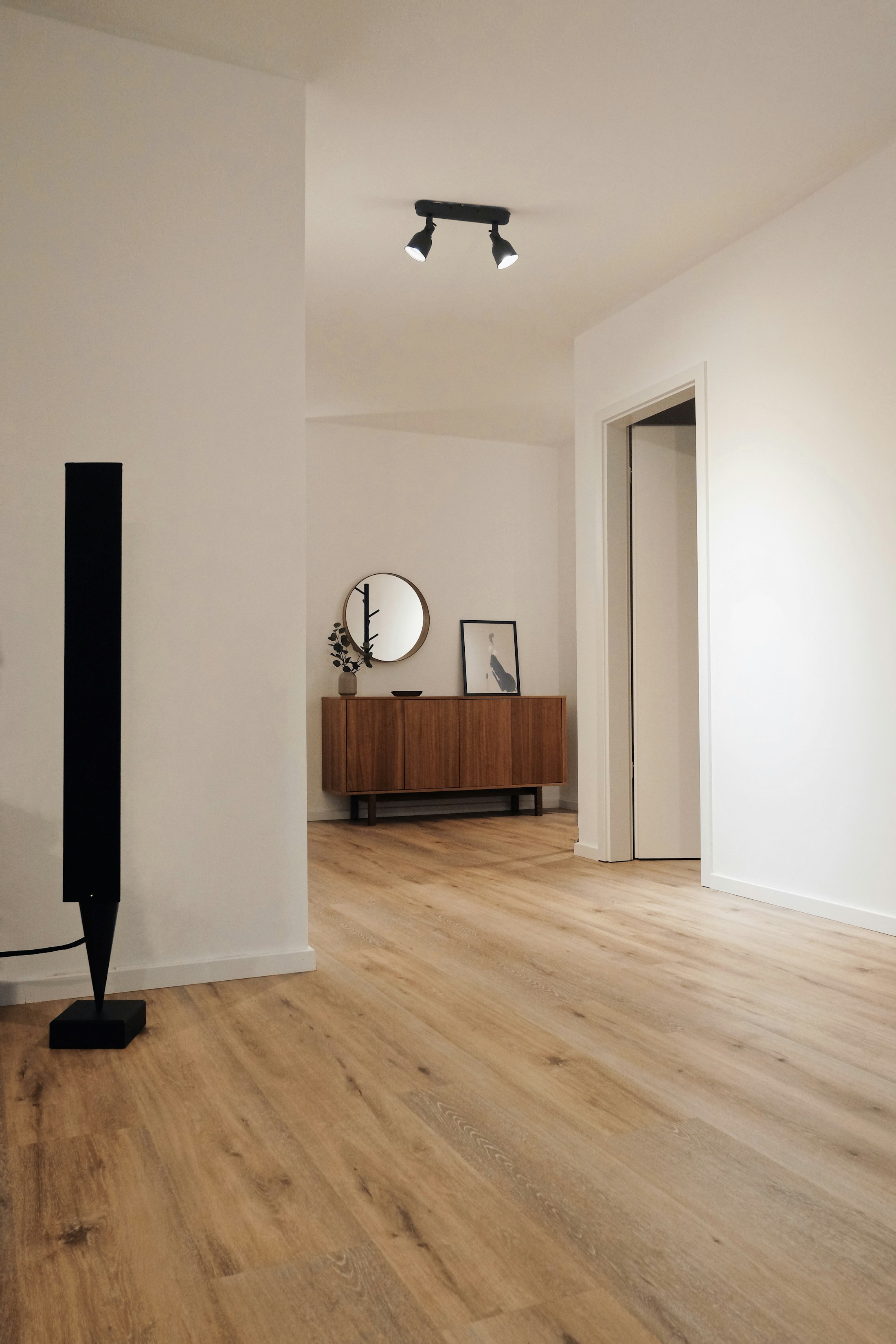 Stanza ristrutturata con parquet chiaro e pareti rasate e tinteggiate di bianco